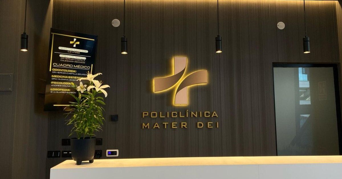 Recepción con lamas de madera oscura y el rótulo dorado retroiluminado de Policlínica Mater Dei