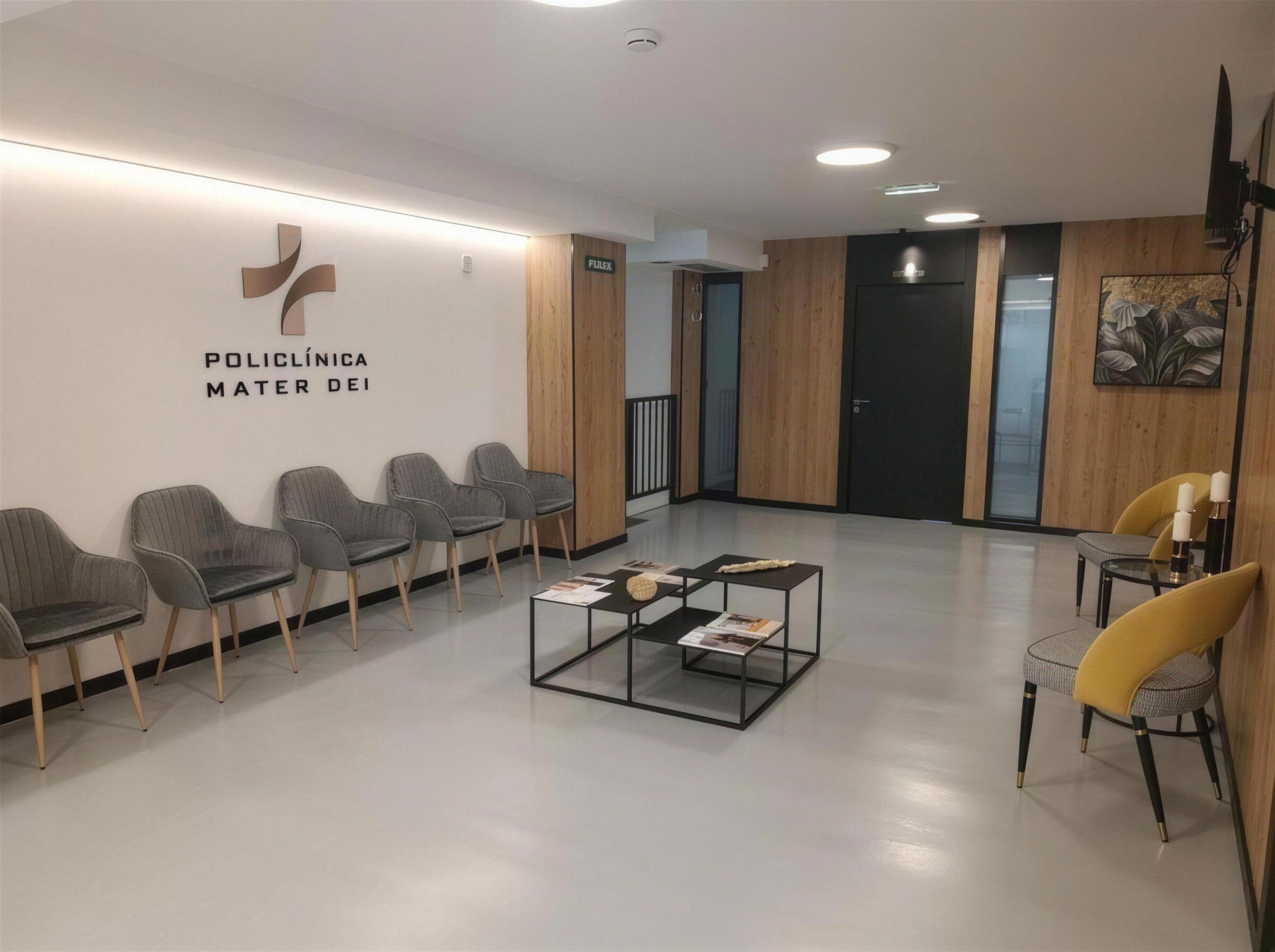Sala de espera con sillones grises, mesa baja y el logotipo de la clínica